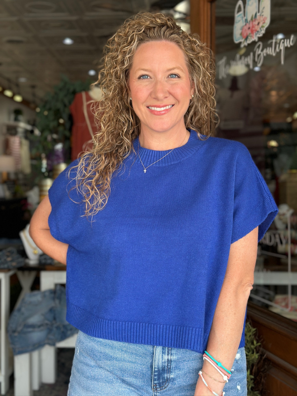 Woman wearing a blue sweater and jeans standing in a store.