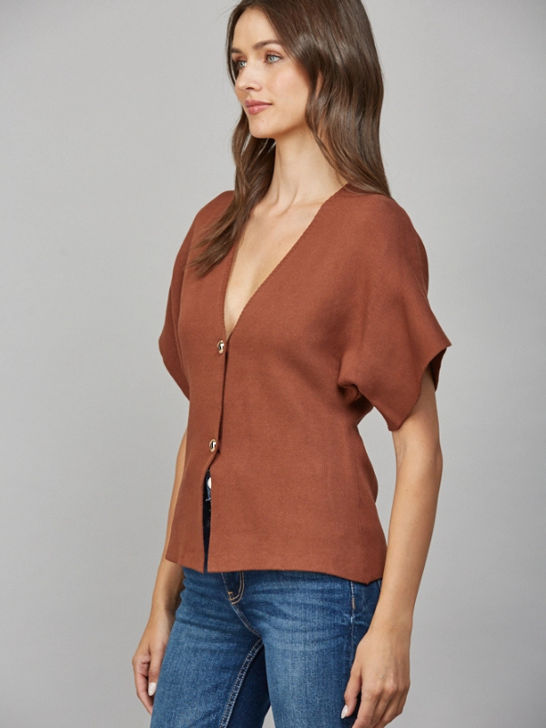 Woman wearing a brown top and blue jeans on a gray background