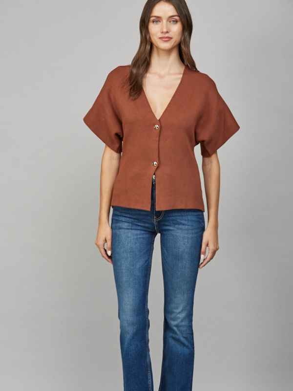 Woman wearing a brown top and blue jeans on a gray background