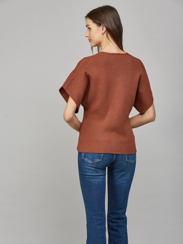 Woman wearing a brown top and blue jeans on a gray background