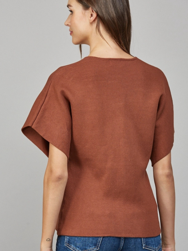 Woman wearing a brown sweater against a gray background