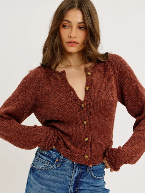 Woman wearing a brown knitted cardigan and blue jeans on a white background