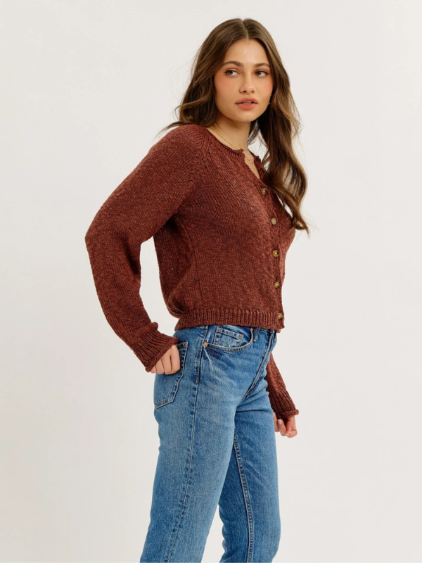 Woman wearing a brown sweater and blue jeans on a white background