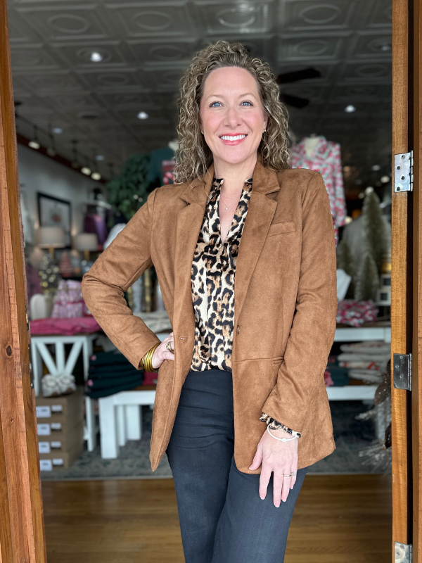 Woman in a brown blazer and leopard print top standing in a store.
