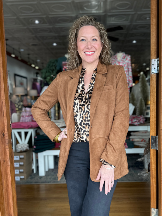 Woman in a brown blazer and leopard print top standing in a store.