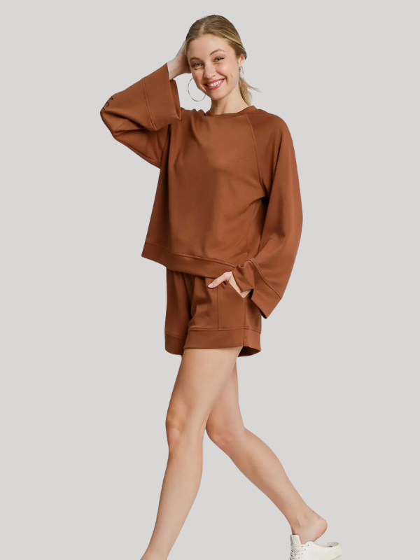 Woman wearing a brown sweatshirt and shorts set on a plain background