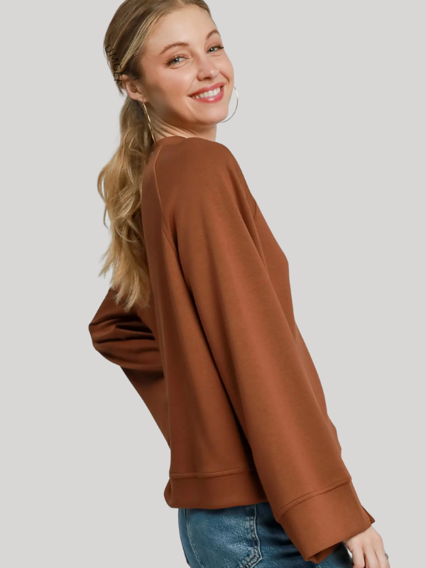 Woman wearing a brown sweater and blue jeans on a light gray background