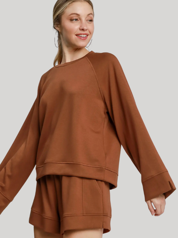 Woman wearing a brown sweatshirt and shorts set on a plain background