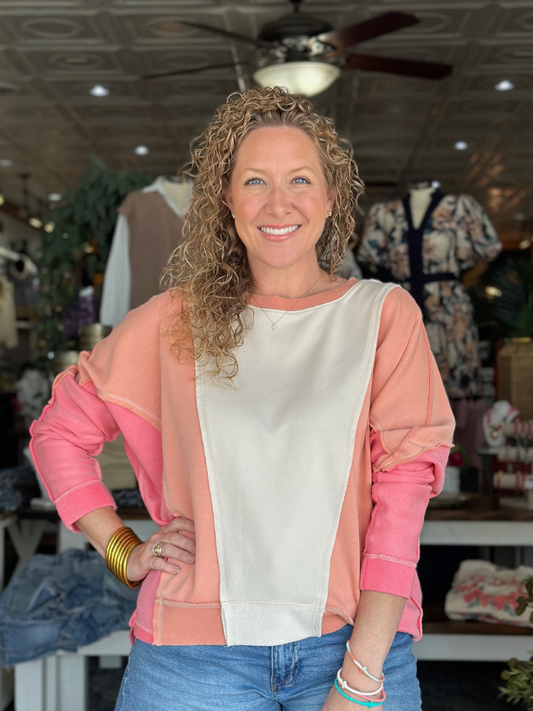 Woman wearing a pink and white top with a blurred store interior background