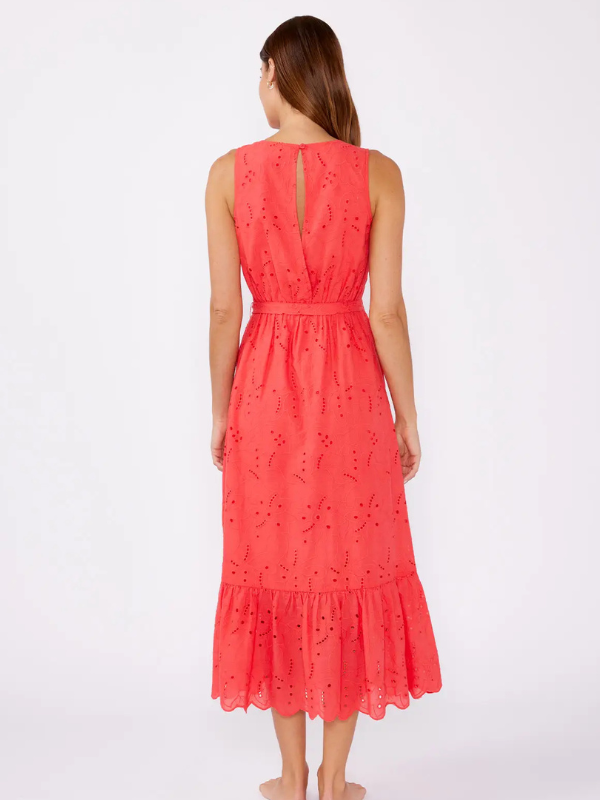 Woman wearing a coral dress with intricate cut-out patterns on a white background