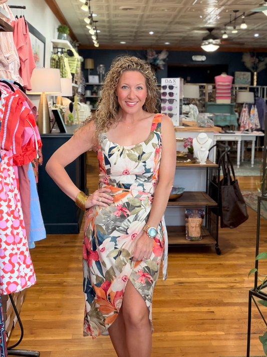 Woman in a floral dress standing in a store with clothing and decor in the background