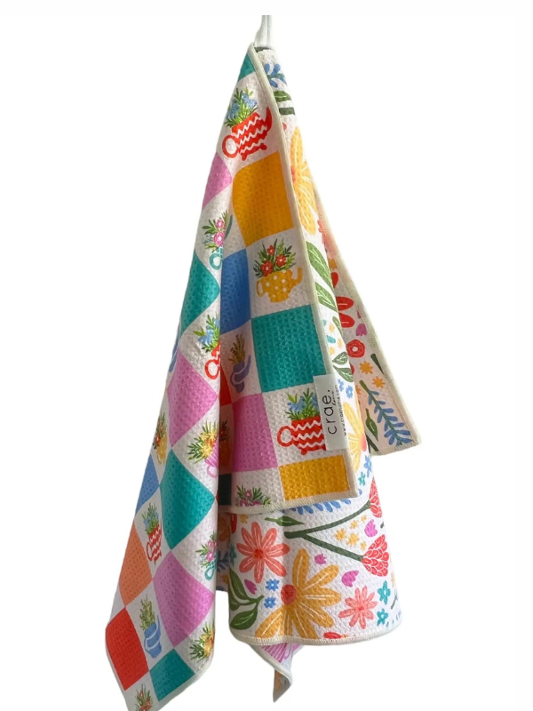 Colorful patchwork towel with floral patterns hanging on a white background