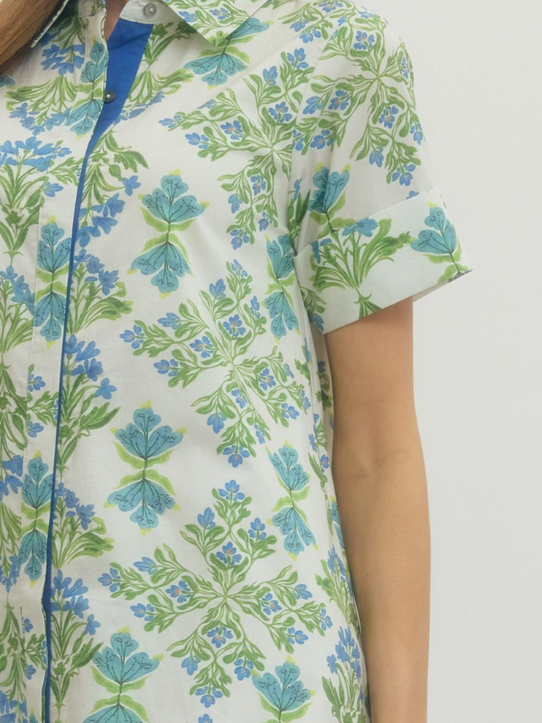 Close-up of a person wearing a floral patterned shirt with blue and green leaves on a white background