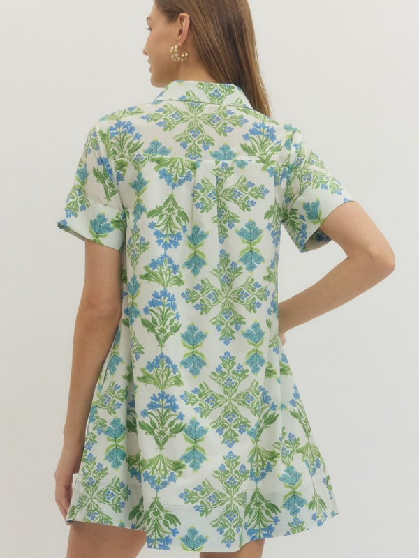 Woman wearing a floral dress with green and blue patterns on a white background