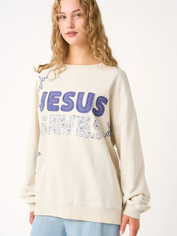 Person wearing a cream sweatshirt with 'Jesus' printed in blue and floral designs on a white background