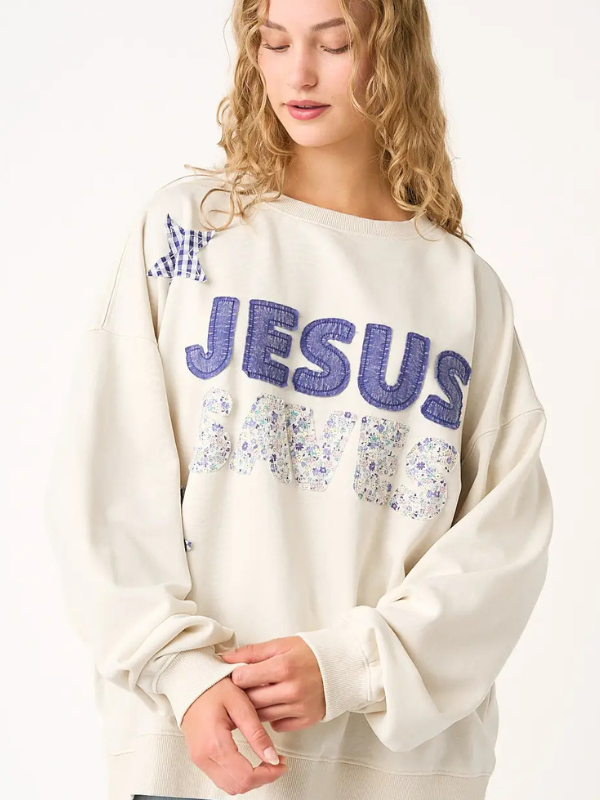 Person wearing a white sweatshirt with 'MY JESUS' text and floral patterns on a plain background