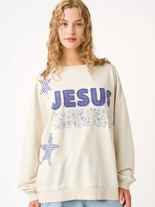 Person wearing a cream sweatshirt with 'Jesus Loves Me' text and star designs.