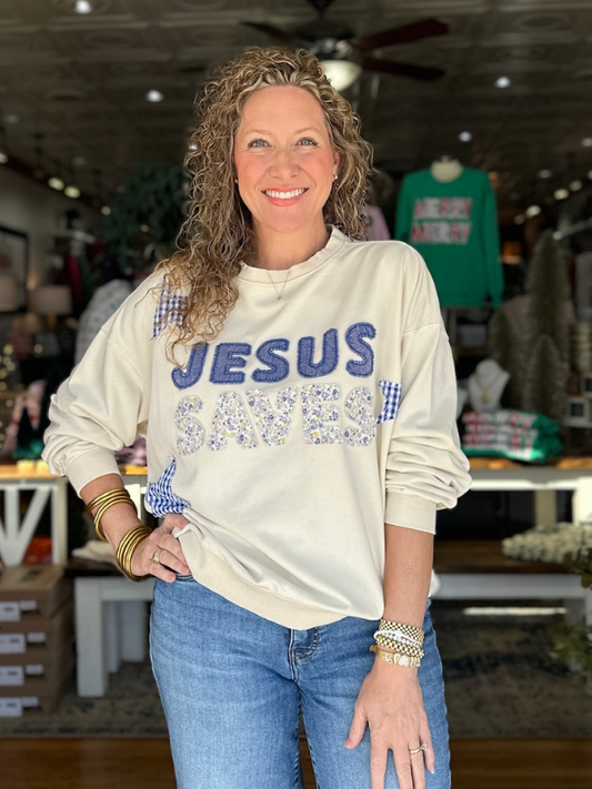 Woman wearing a white sweatshirt with 'Jesus' printed on it in a store setting.