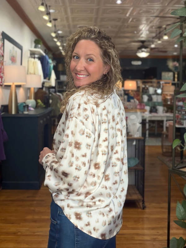 woman wearing a cream and brown abstract button up satin top 