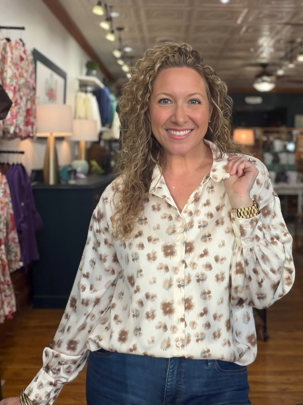 woman wearing a cream and brown abstract button up satin top 
