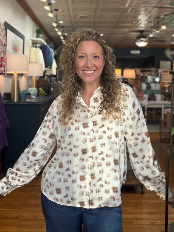 woman wearing a cream and brown abstract button up satin top 
