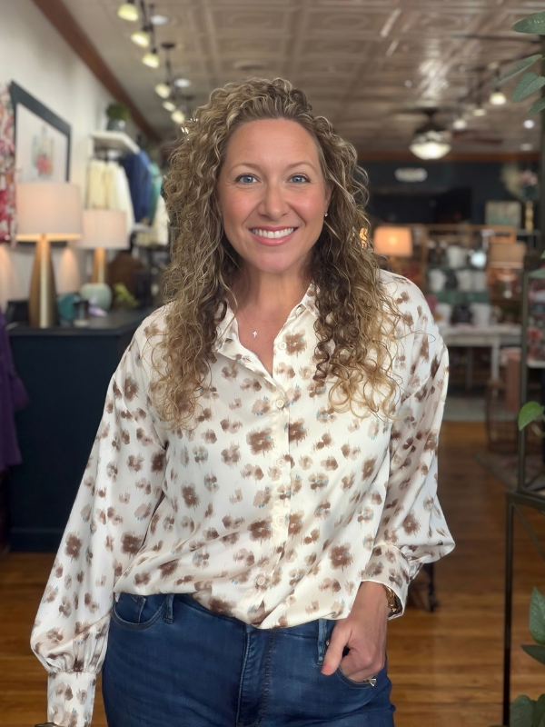 woman wearing a cream and brown abstract button up satin top 