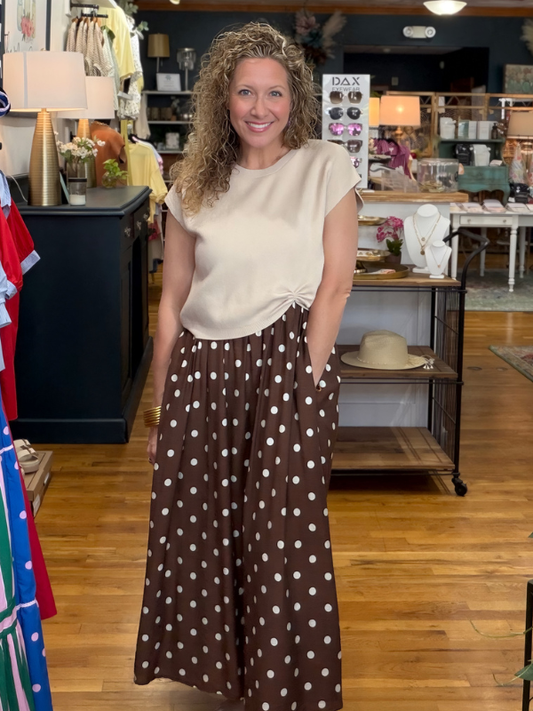 Woman in a store wearing a white top and brown polka dot skirt
