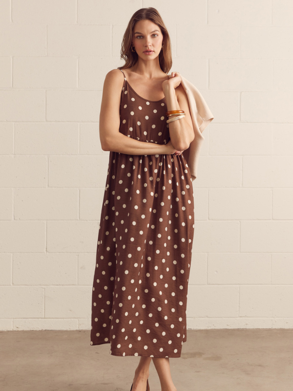 Woman wearing a brown polka dot dress against a light background