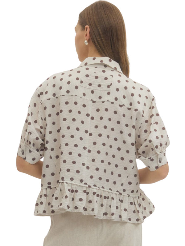 Woman wearing a polka dot blouse with a white background