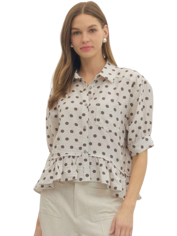 Woman wearing a polka dot blouse with ruffled details on a white background