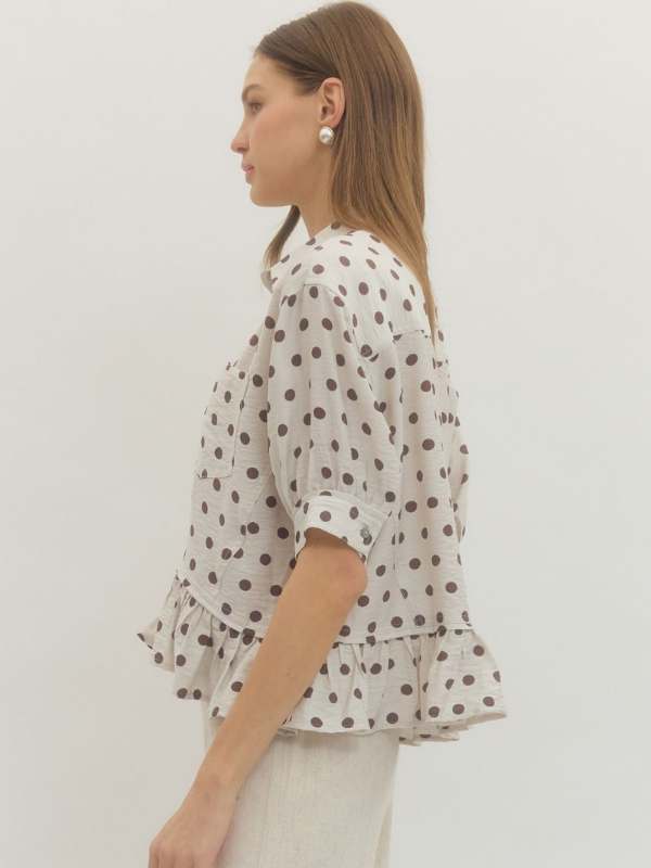 Woman wearing a polka dot blouse against a plain background