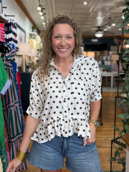 woman wearing a brown and cream polka dot top in a store 