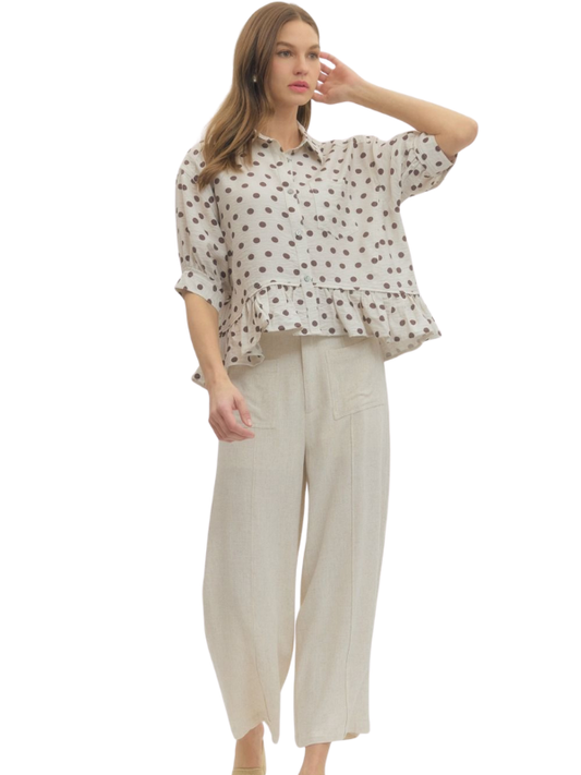 Woman wearing a patterned blouse and beige pants on a white background