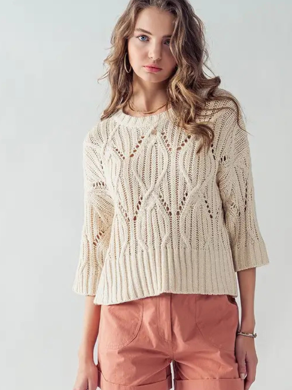 Woman wearing a beige knitted sweater and pink pants on a white background