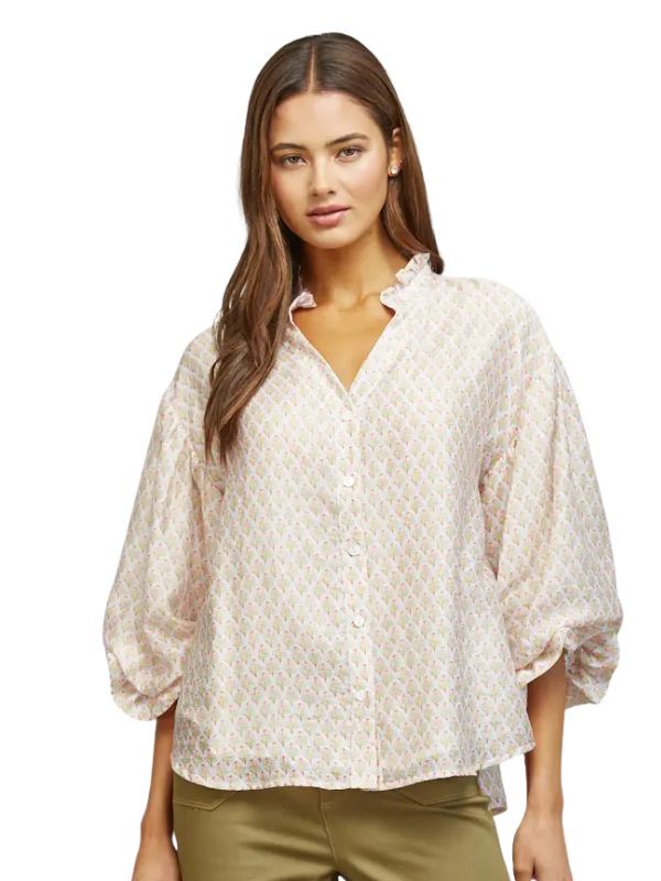 A woman modeling a loose-fitting, short-sleeve button-up blouse with a delicate beige and white geometric pattern, paired with olive green pants, against a plain white background.