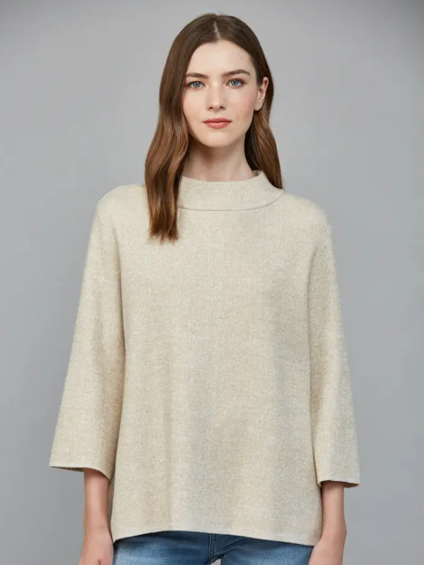 Woman wearing a beige sweater against a gray background