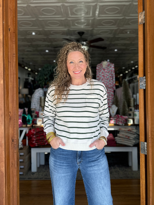 Woman wearing a striped sweater and jeans standing in a store.