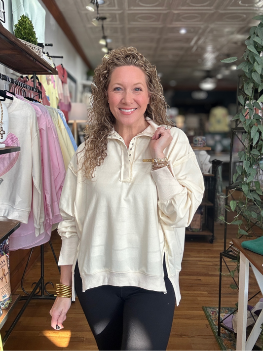 Woman in a store wearing a cream-colored jacket and black leggings, holding a pen.