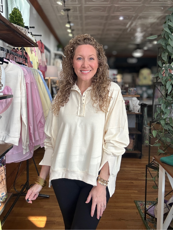Woman standing in a store with clothing racks and decor in the background