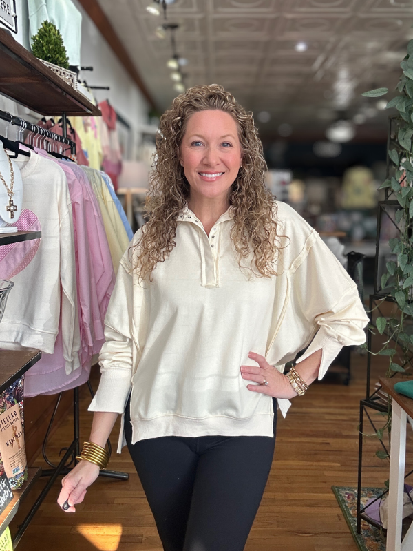 Woman wearing a cream-colored blouse in a store setting