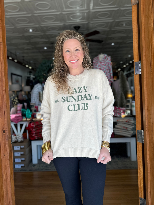 Woman wearing a sweater with 'Lazy Sunday Club' text in a store setting