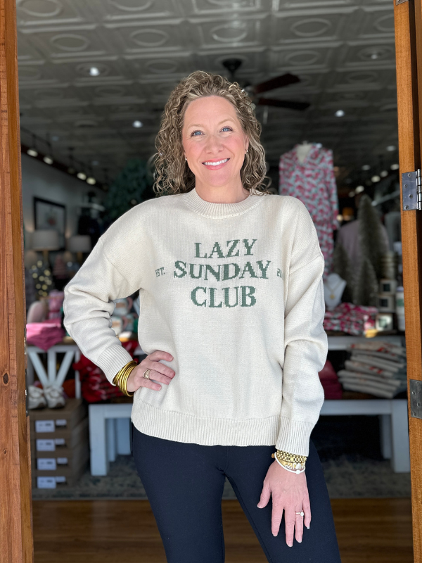 Woman wearing a sweater with 'Lazy Sunday Club' text in a store setting
