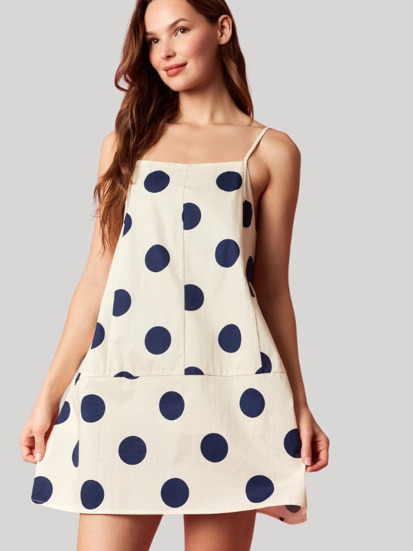 Woman wearing a polka dot dress with a plain background