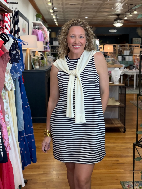Woman wearing a black and white striped dress with a scarf in a clothing store.