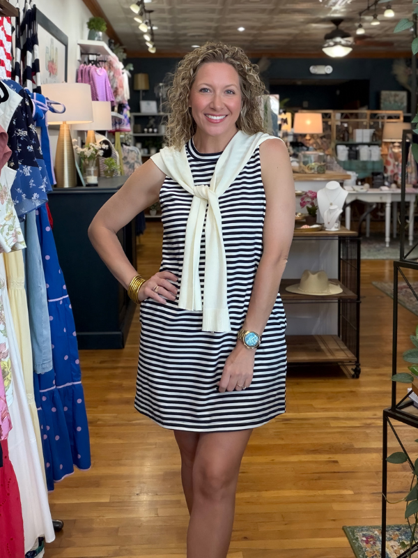 Woman in a striped dress with a scarf standing in a store.
