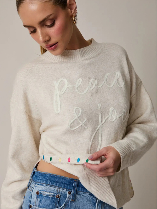 woman wearing a Cream Peace + Joy Sweater
