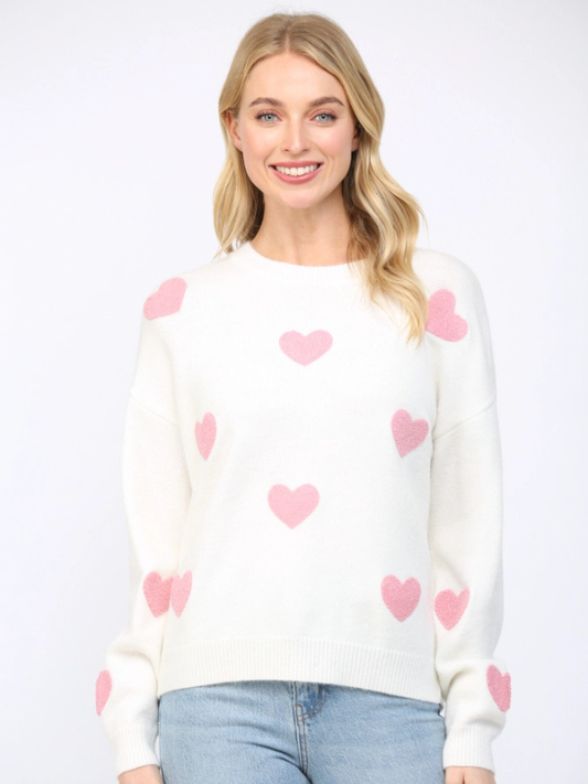 Woman wearing a white sweater with pink heart patterns on a white background