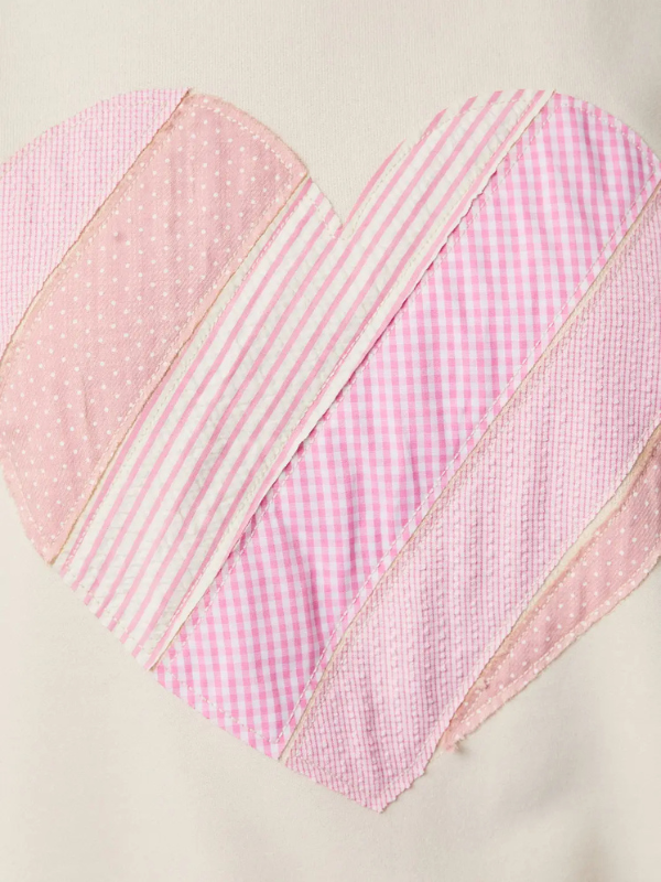 Heart-shaped patchwork quilt with pink and white patterns on a beige background