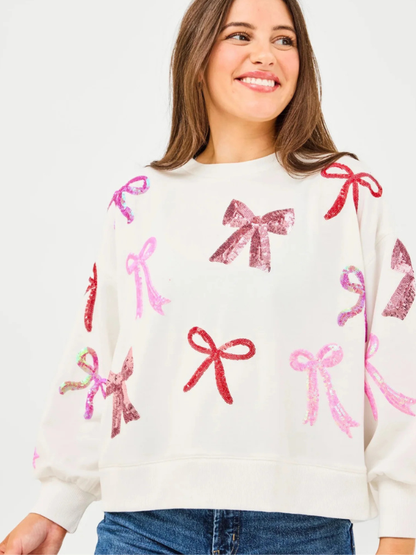 Woman wearing a sweater with pink and red bows on a white background