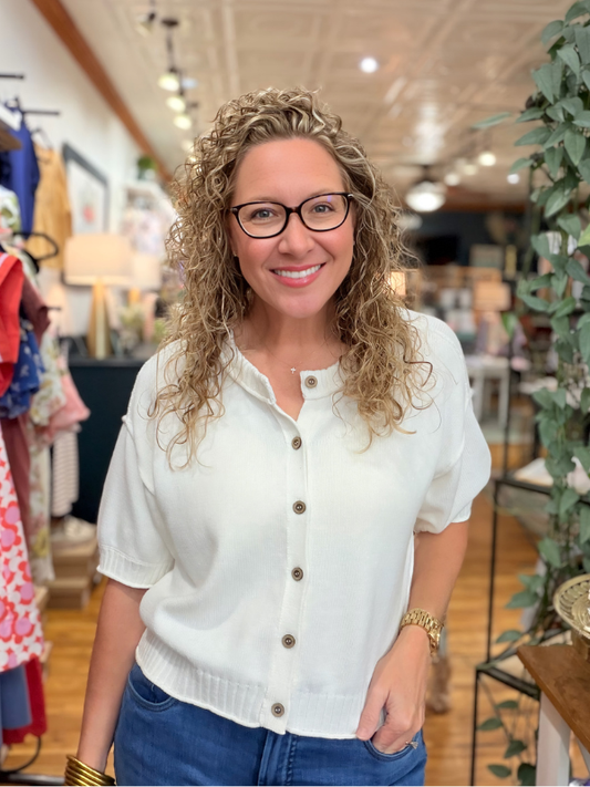 Woman wearing a white blouse with buttons in a store setting